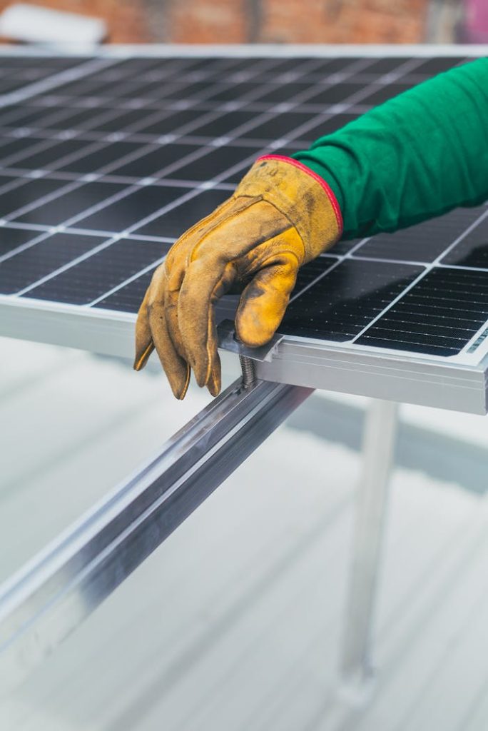 Close-up of a worker's hand in protective glove installing a solar panel.